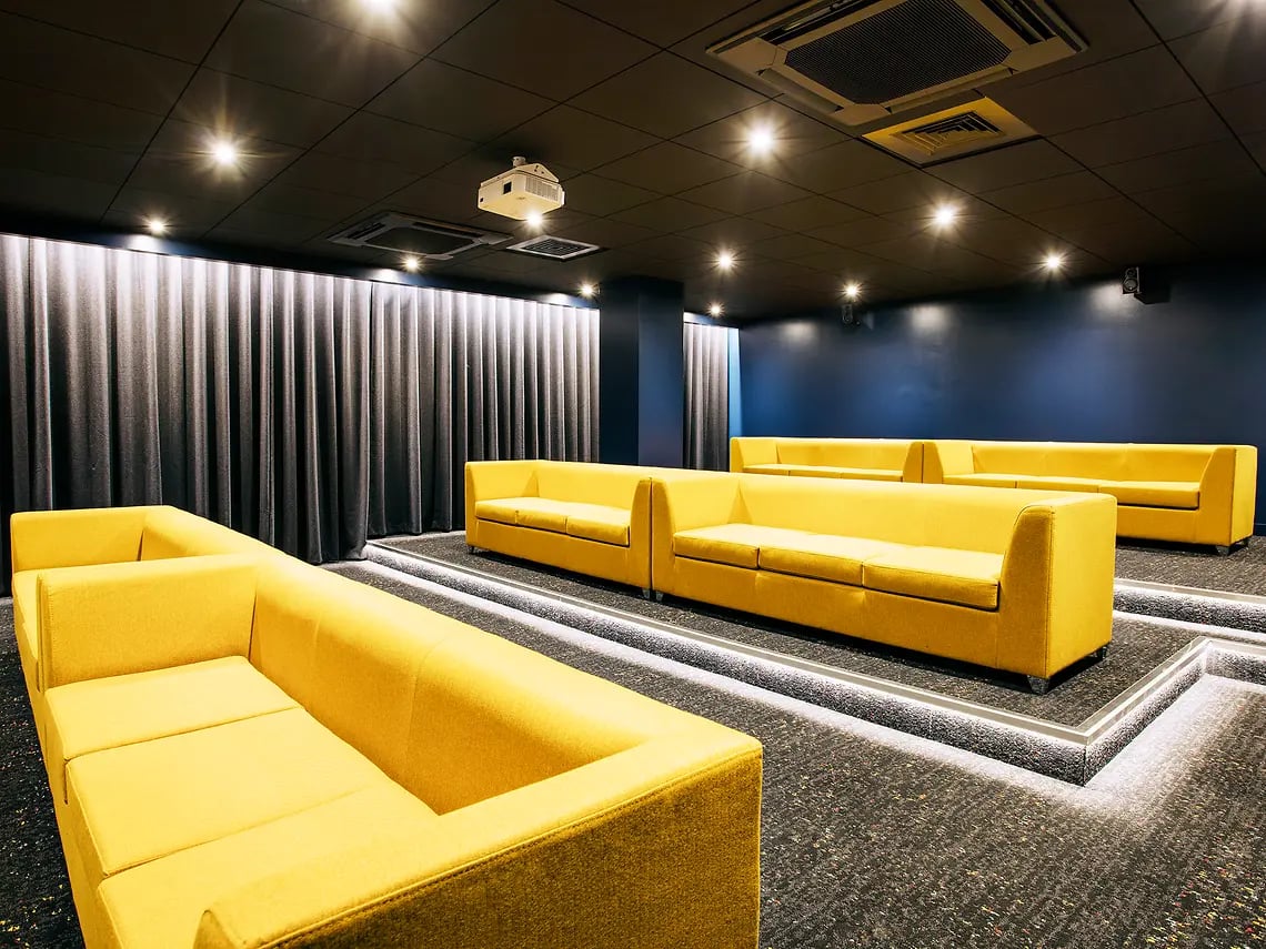 Yellow sofas and projector in entertainment room at The Curve in London Student Accommodation