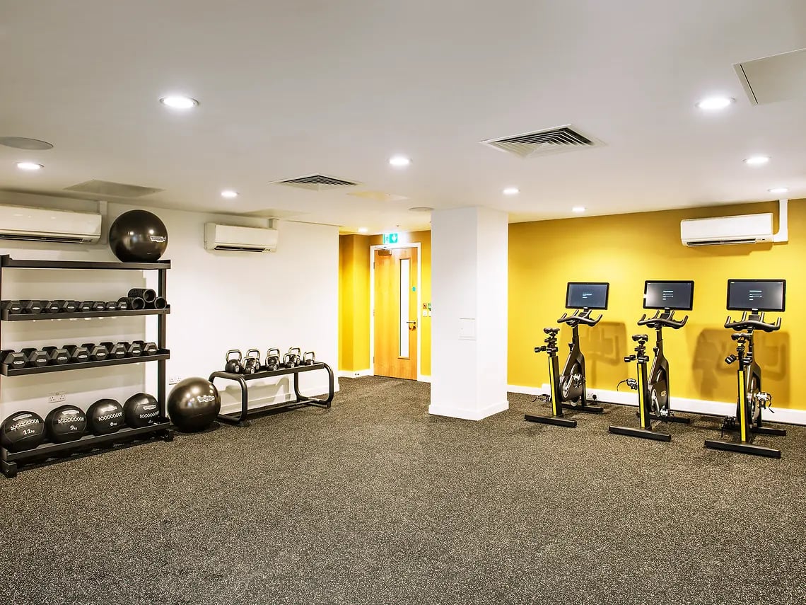 Dumbbells kettlebells exercise bikes gym area at The Curve in London Student Accommodation