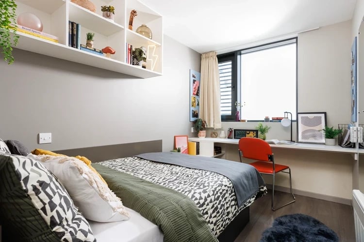 Bed pillows desk chair and shelves bedroom at Olympic Way in London Student Accommodation