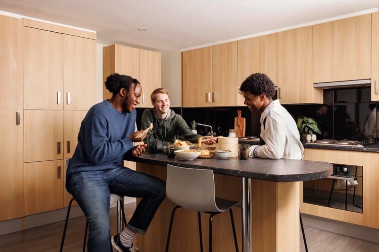 Three students eating at kitchen counter kitchen at Olympic Way in London Student Accommodation