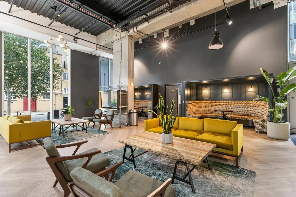 Yellow couches wooden tables and seating booths living room at Chapter Kings Cross in London Student Accommodation