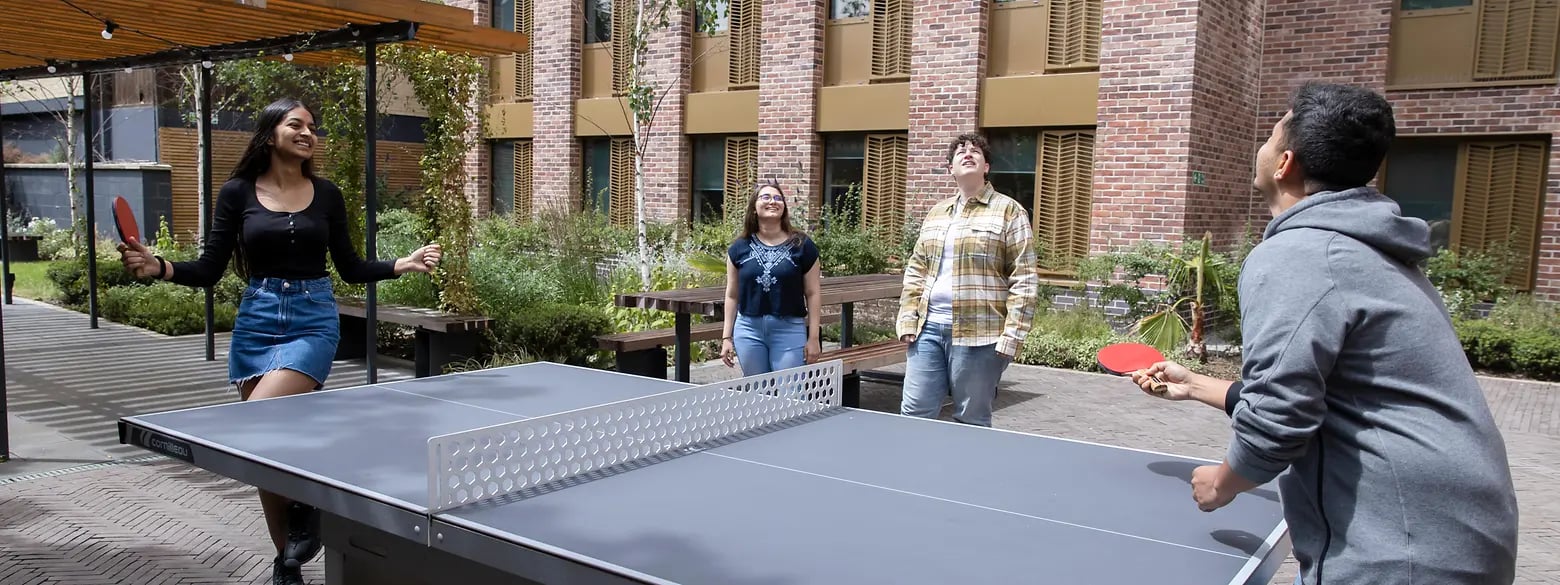 Four students playing table tennis outdoors Courtyard at The Valentine London in London Student Accommodation