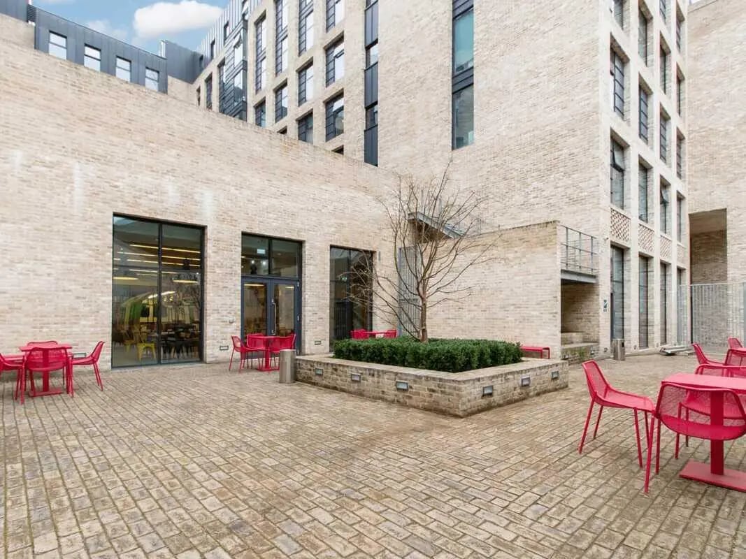 Red tables and chairs courtyard exterior at Spring Mews in London Student Accommodation