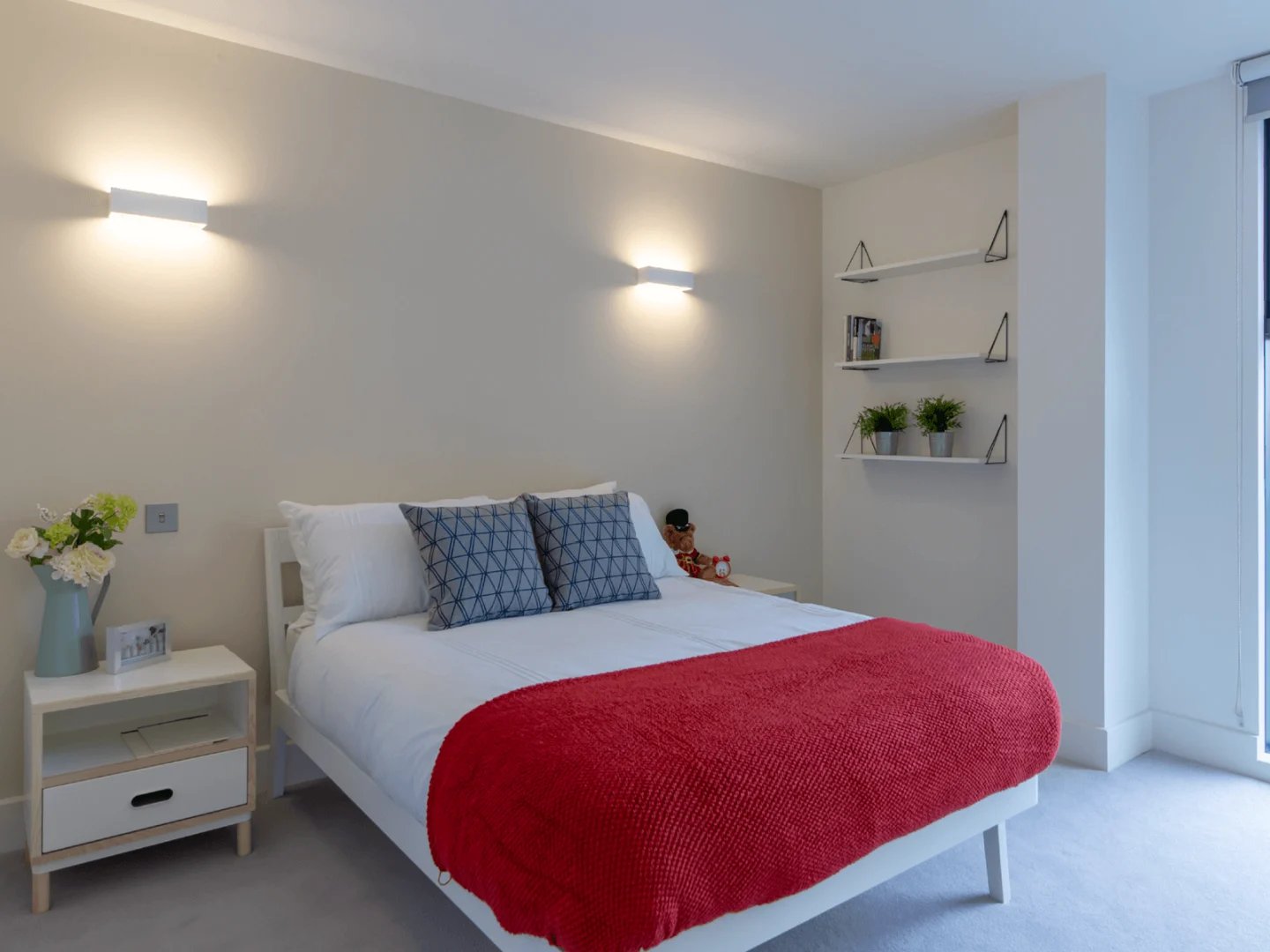 Bed with red blanket two pillows bedside table bedroom at Spring Mews in London Student Accommodation