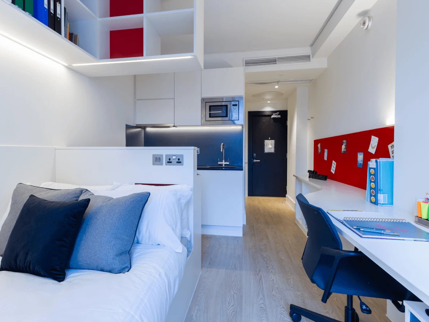 Bed with pillows desk chair and kitchen study bedroom at Spring Mews in London Student Accommodation