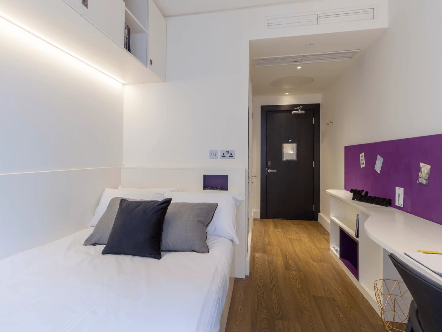 Bed with grey cushions and desk area bedroom at Spring Mews in London Student Accommodation