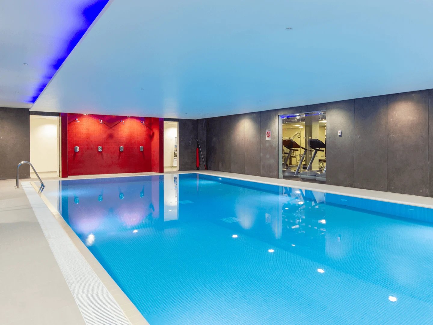 Indoor swimming pool with showers and gym area Swimming pool at Spring Mews in London Student Accommodation