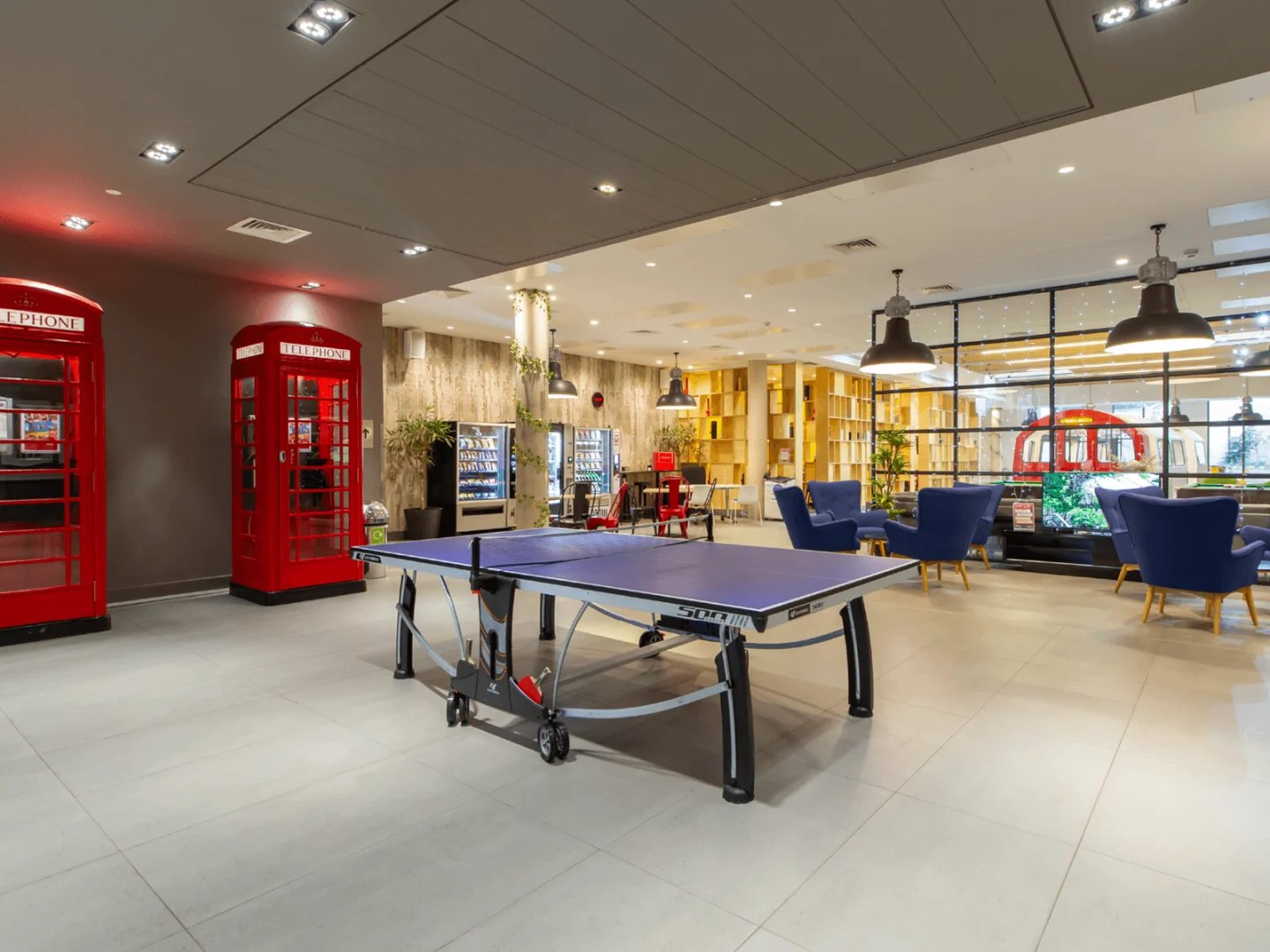 Ping pong table red phone booths vending machines chairs living area at Spring Mews in London Student Accommodation