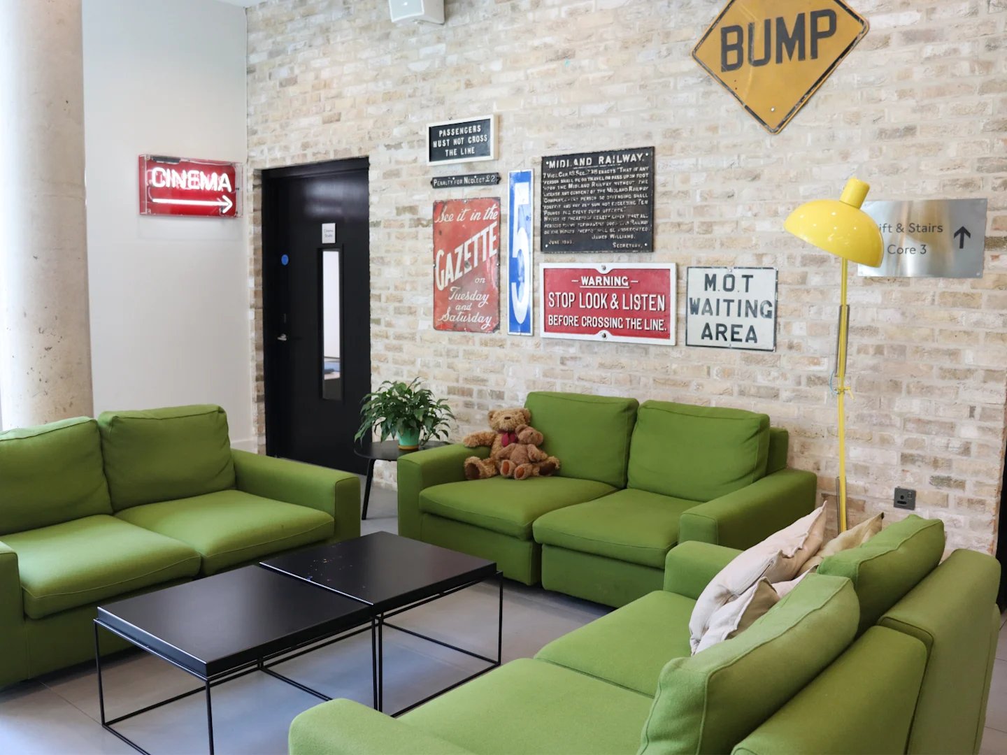 Green sofas black tables vintage signs living room at Spring Mews in London Student Accommodation