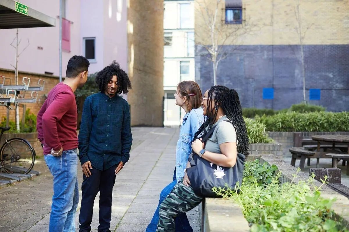 Students chatting outdoors near buildings and bike rack exterior at Collegiate Dashwood Studios in London Student Accommodation