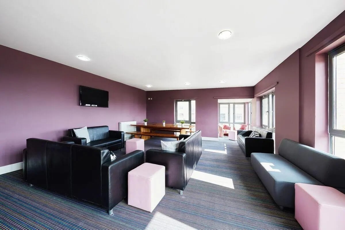 Black sofas pink cubes wooden table living room at Collegiate Dashwood Studios in London Student Accommodation