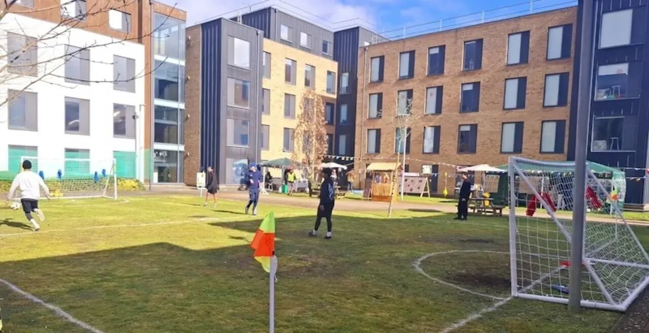 People playing soccer with modern buildings exterior at Kendrick Hall in Reading Student Accommodation