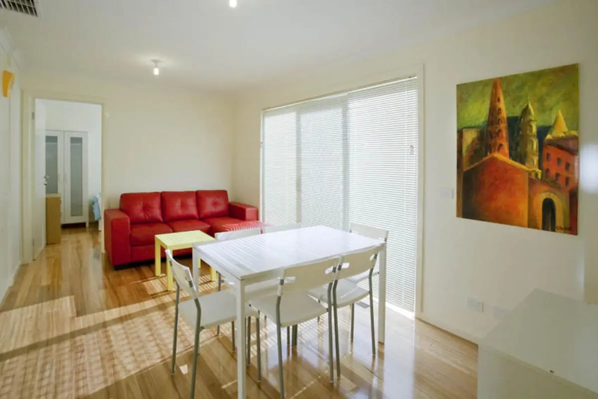 Red sofa white table chairs painting living room at Sunset House in Melbourne Student Accommodation