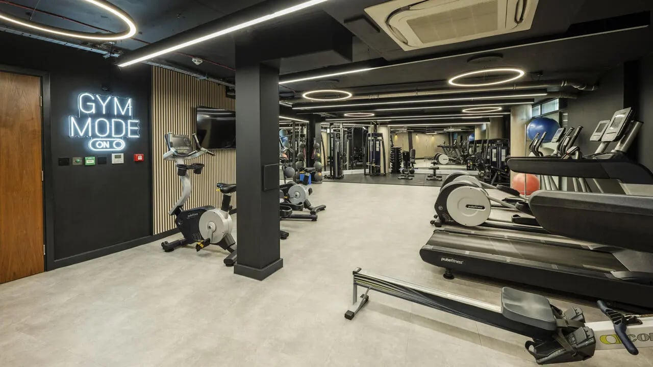 Gym equipment with neon sign gym mode living room at The Printworks in Exeter Student Accommodation