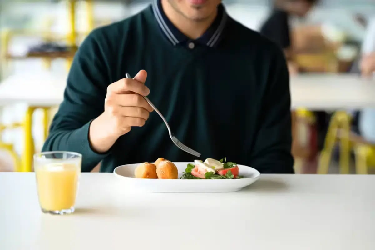 Student eating lunch salad and fried food dining area at Scape Victoria Street in Melbourne Student Accommodation