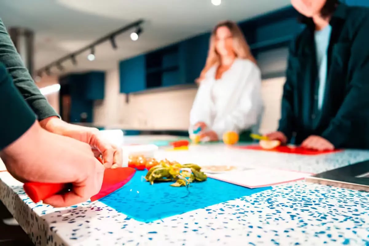Hands chopping vegetables on kitchen counter with blue cabinets Kitchen at Scape Lincoln College in Melbourne Student Accommodation