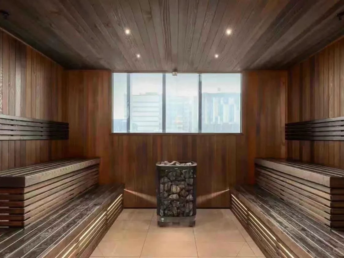 Wooden sauna benches with stone heater and window sauna at Belong Melbourne CBD in Melbourne Student Accommodation