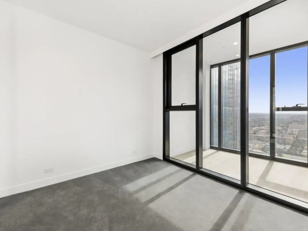 Empty white room with grey carpet and windows bedroom at Belong Melbourne CBD in Melbourne Student Accommodation