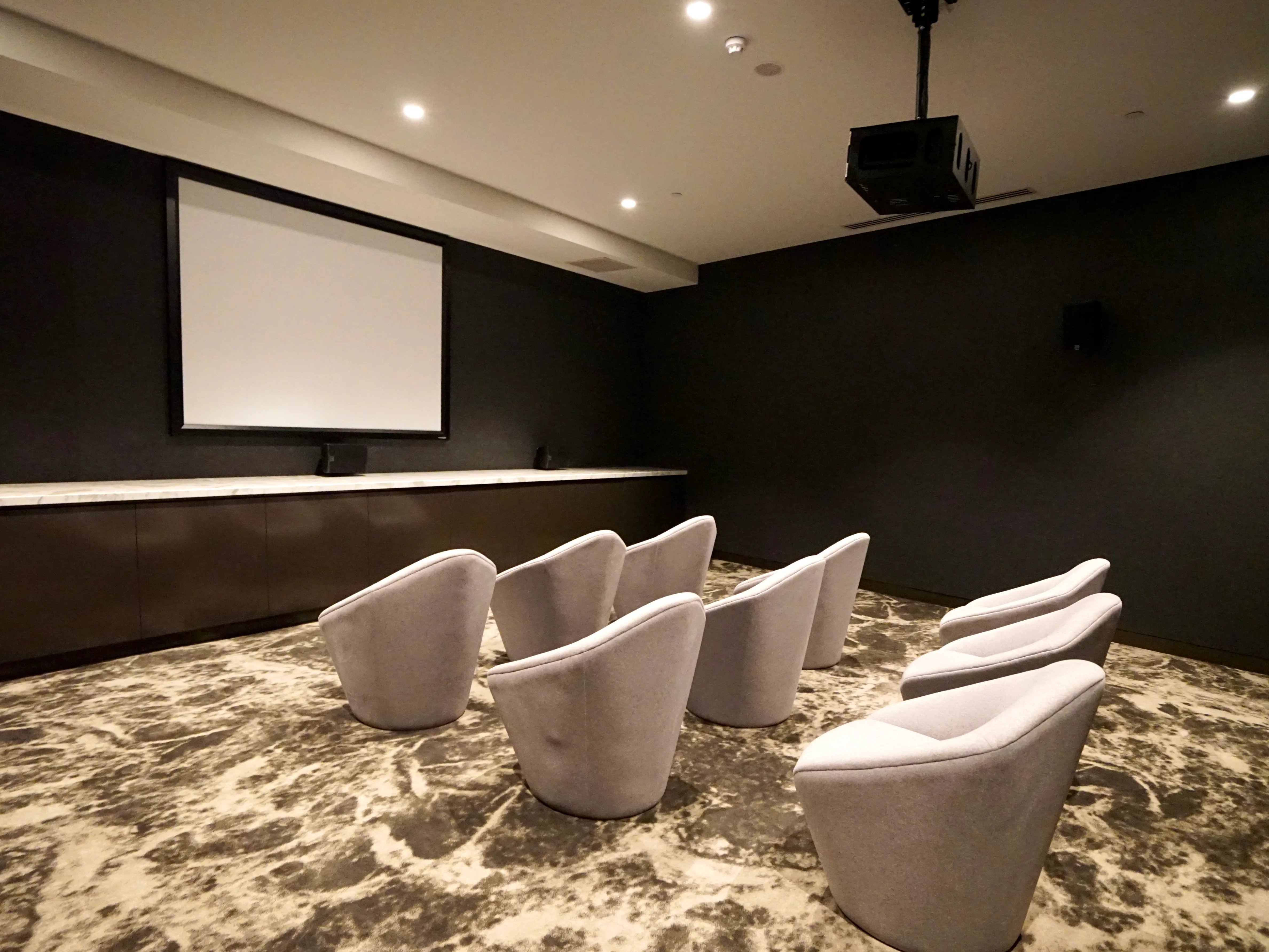 Grey chairs before projection screen cinema room at Belong Melbourne CBD in Melbourne Student Accommodation