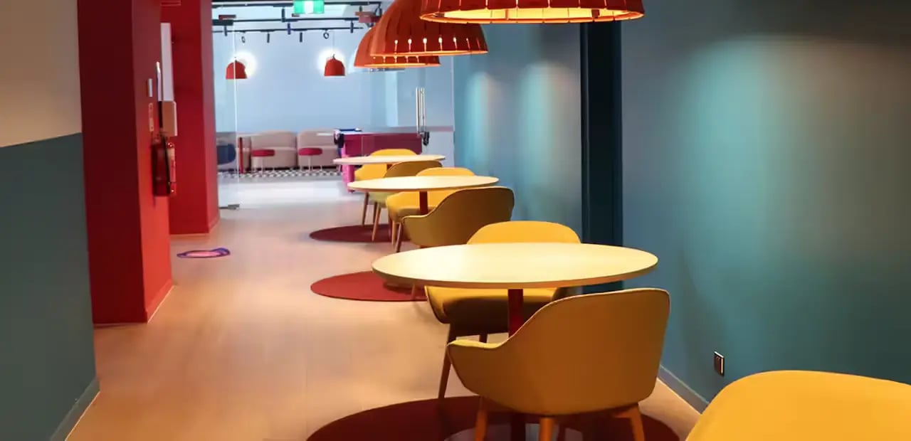Yellow chairs and tables in a lounge area at Scape Carlton in Melbourne Student Accommodation