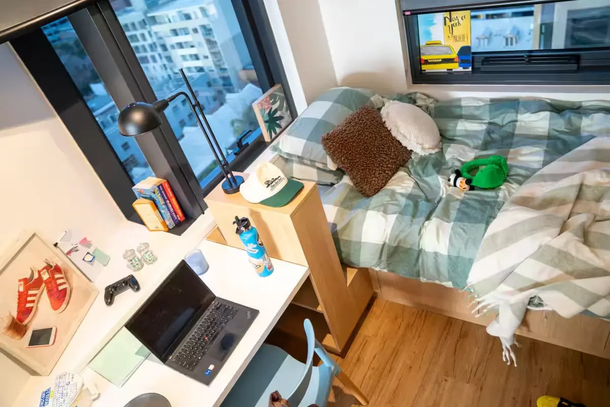 Bed laptop desk and city view bedroom at Scape Carlton in Melbourne Student Accommodation