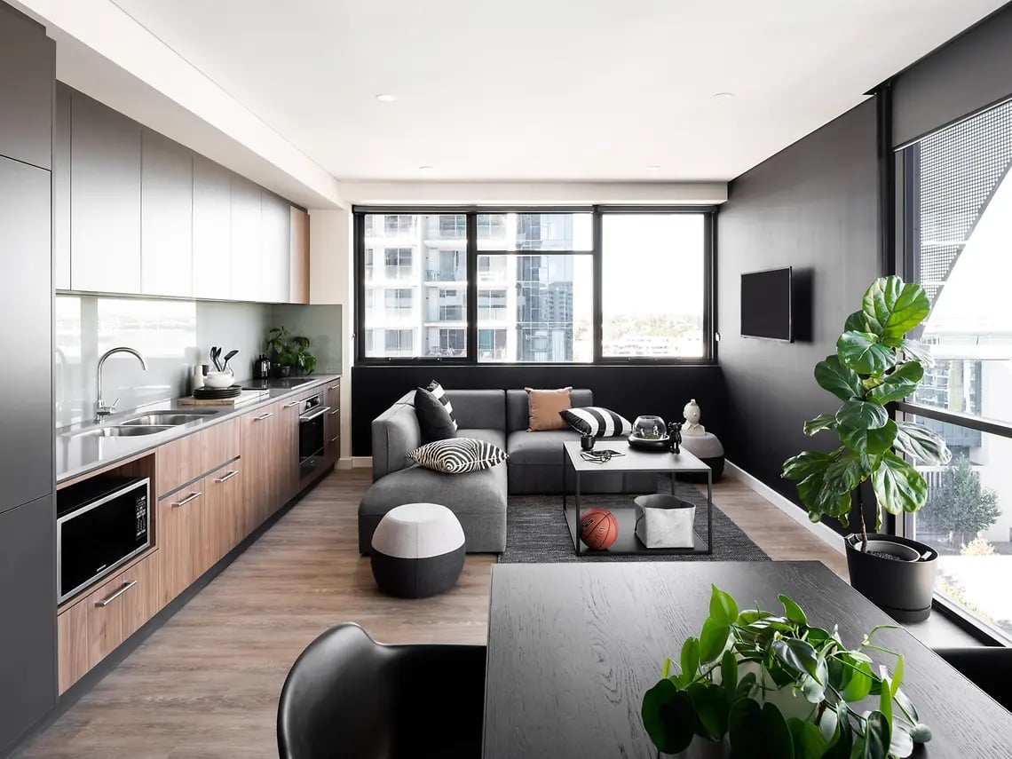 Modern kitchen with grey sofa and large plant living room at Yugo Perth City in Perth Student Accommodation