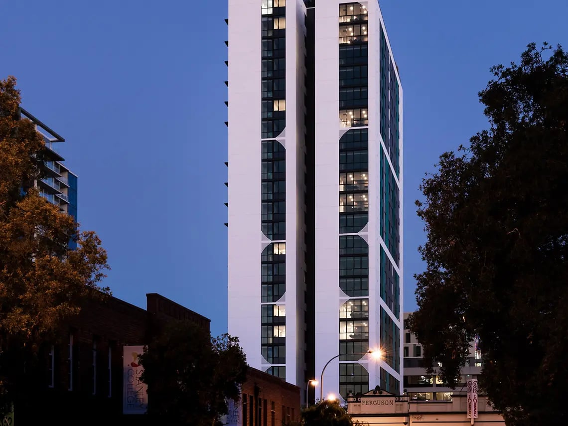 Modern high rise building with lit windows exterior at Yugo Perth City in Perth Student Accommodation