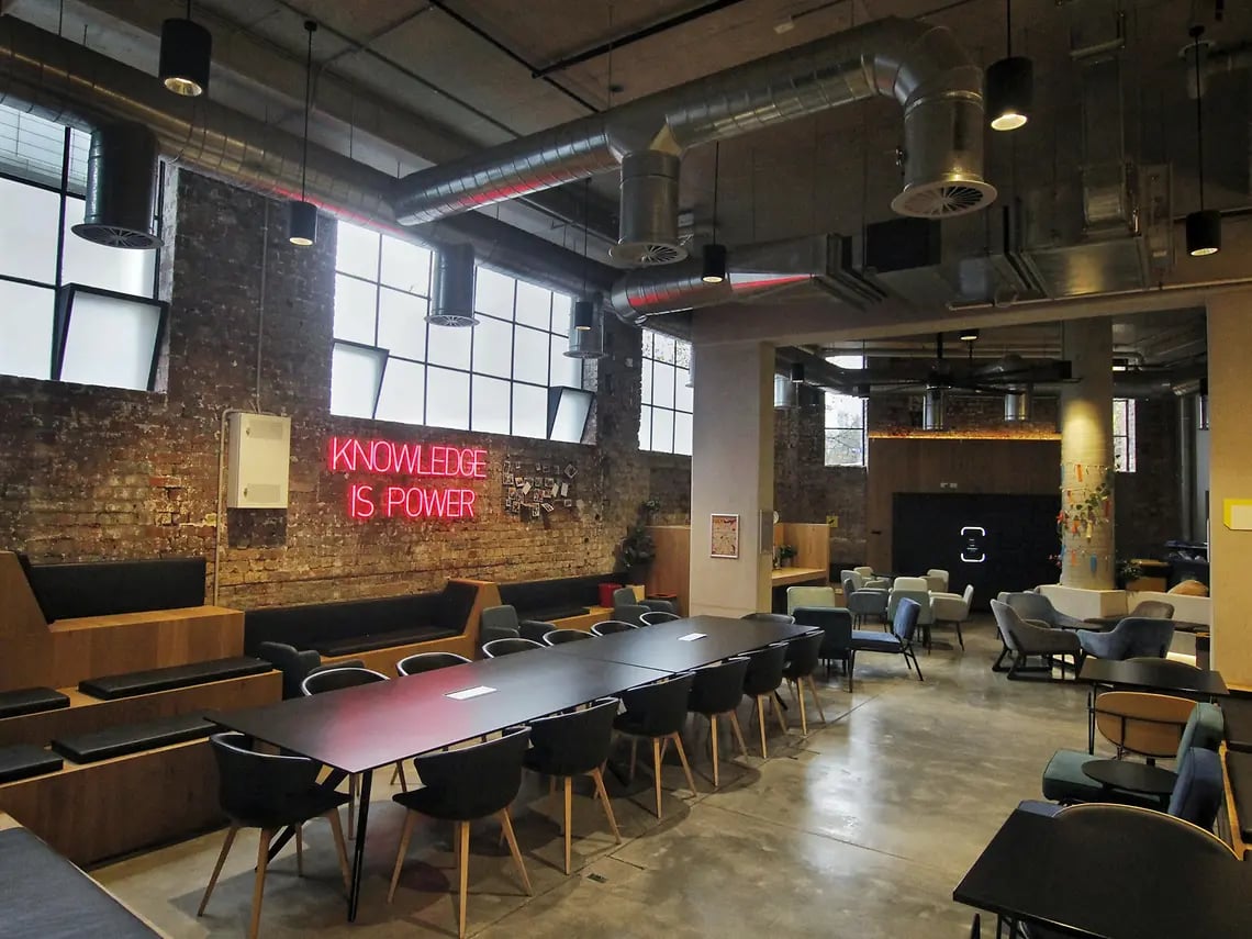 Long table with chairs and neon sign living room at Yugo University Square Melbourne in Melbourne Student Accommodation