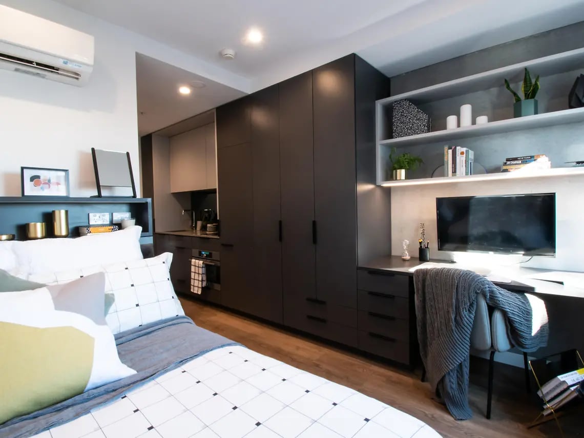 Bed desk wardrobe and kitchen studio apartment at Yugo University Square Melbourne in Melbourne Student Accommodation