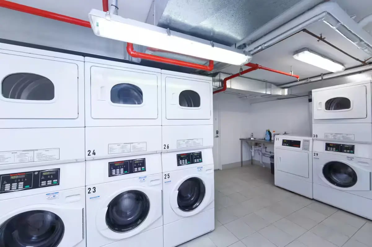 Laundry room with stacks of washing machines dryers living room at Scape Merivale in Brisbane Student Accommodation