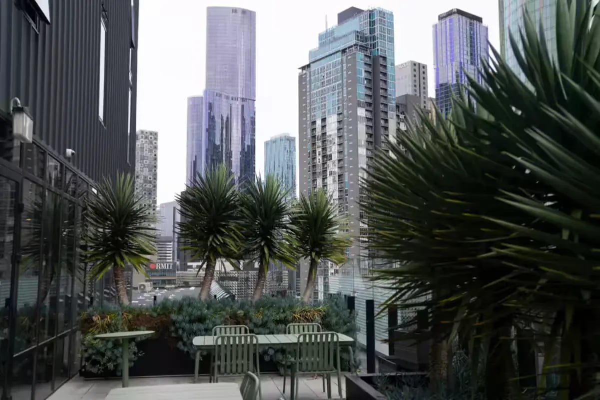 Tables chairs plants with cityscape exterior at Scape Cornell Place in Melbourne Student Accommodation
