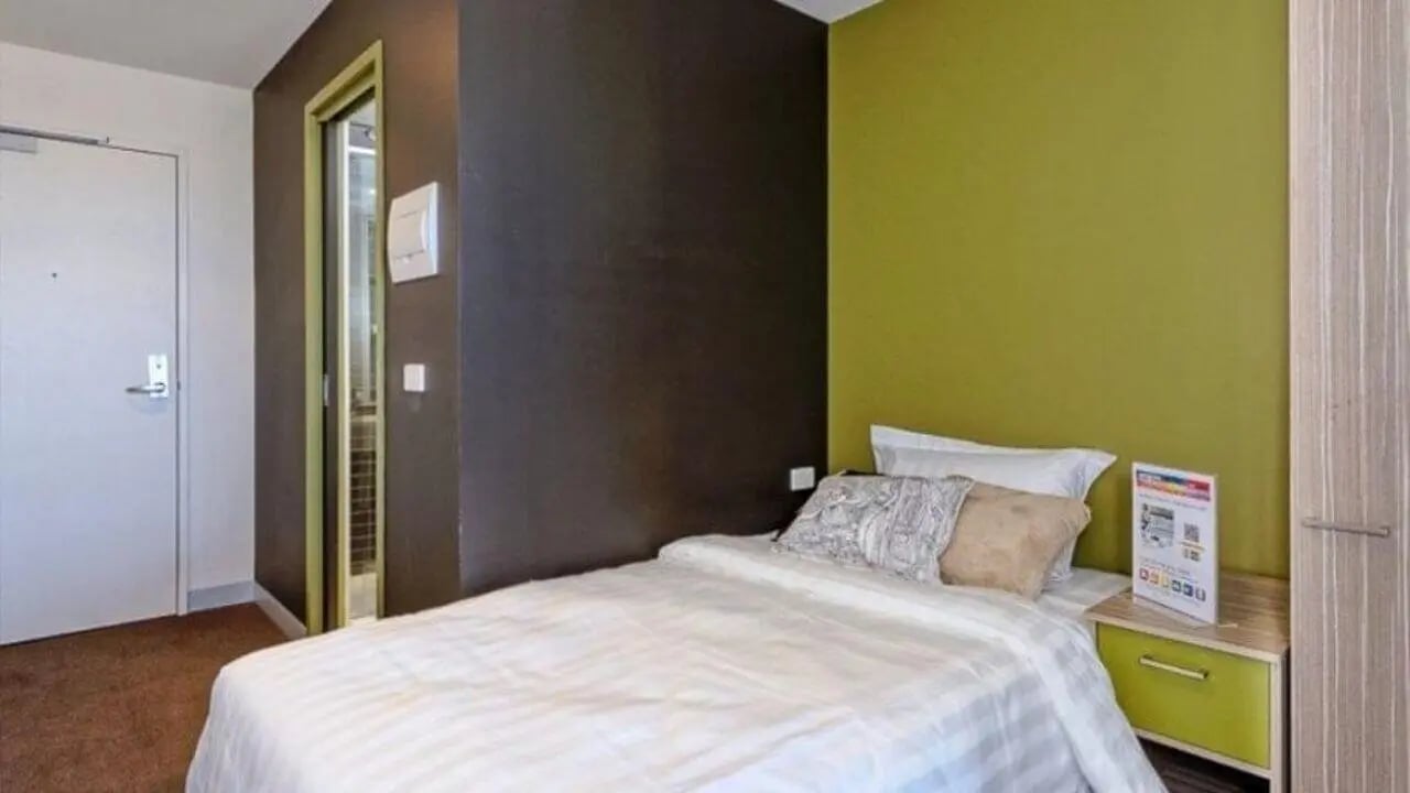 Bed white bedding bedside table framed poster bedroom at Student Living - Vivida in Melbourne Student Accommodation