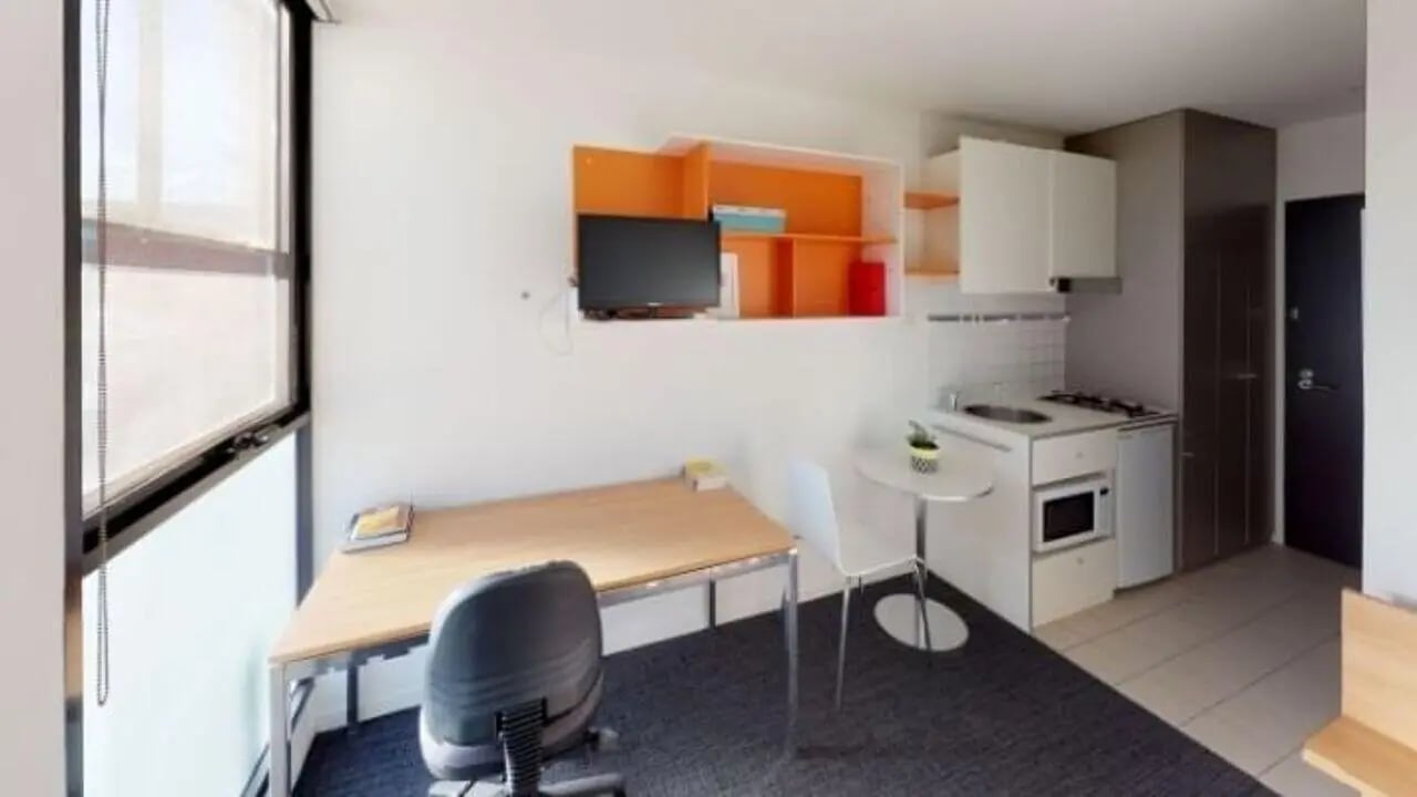 Desk chair TV kitchen counter and microwave living room at Student Living On Campus in Melbourne Student Accommodation
