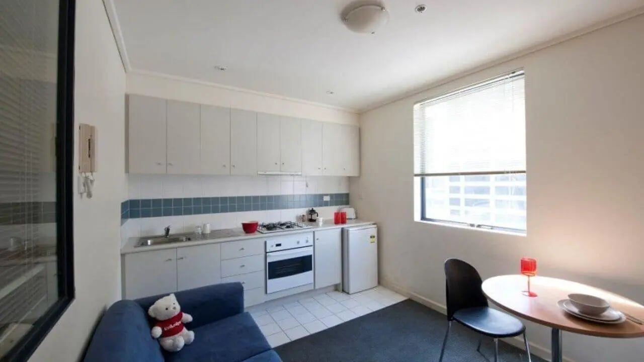 Blue sofa stove sink fridge table kitchen at Student Living On ABeckett in Melbourne Student Accommodation