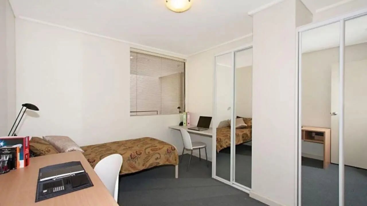 Bed desk chair laptop mirrored closet bedroom at Student Living On ABeckett in Melbourne Student Accommodation