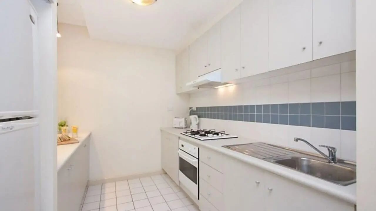White cabinets fridge stove sink tiled backsplash kitchen at Student Living On ABeckett in Melbourne Student Accommodation