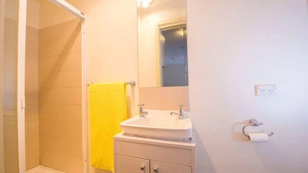 Shower sink yellow towel and toilet paper bathroom at Student Living On ABeckett in Melbourne Student Accommodation