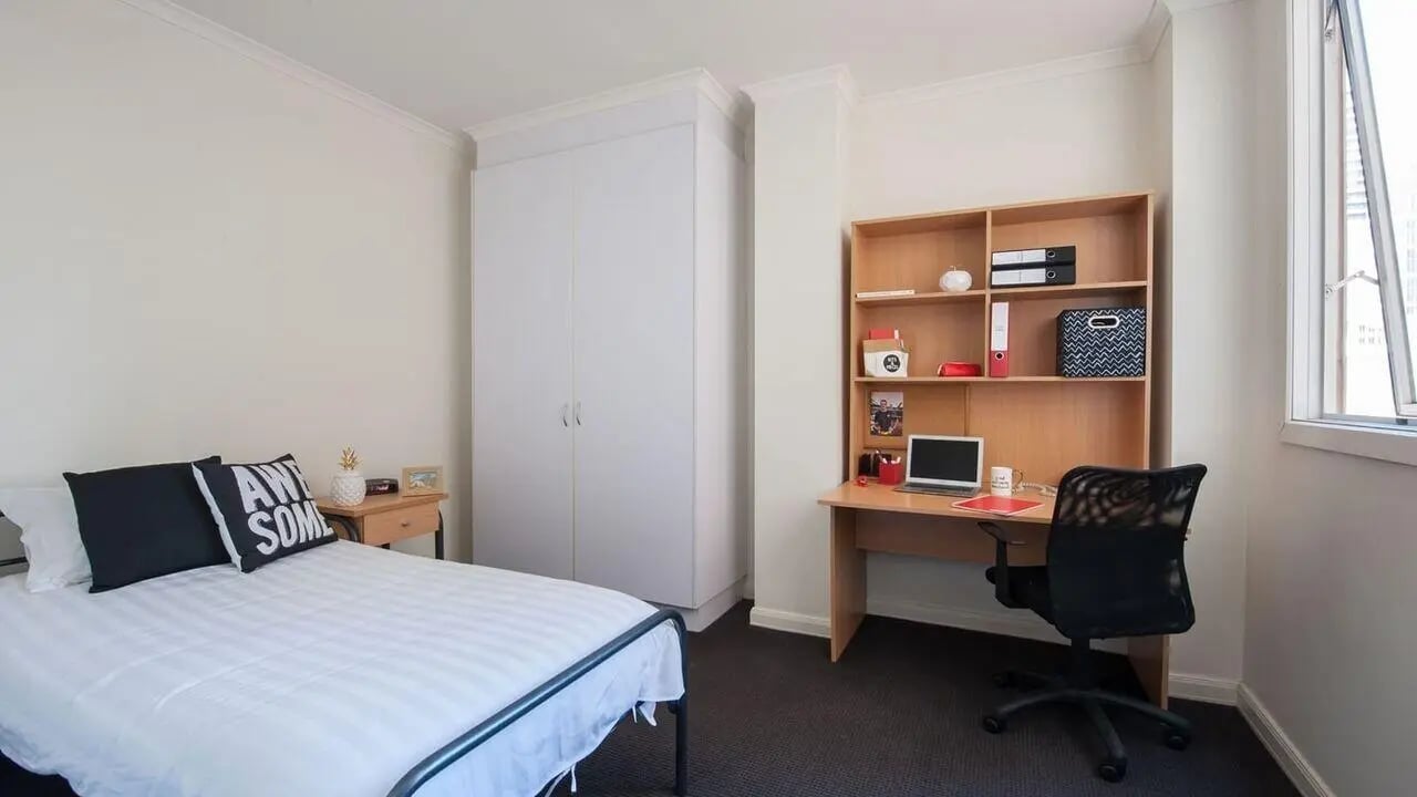 Bed wardrobe desk chair with laptop bedroom at Student Living on Flinders in Melbourne Student Accommodation