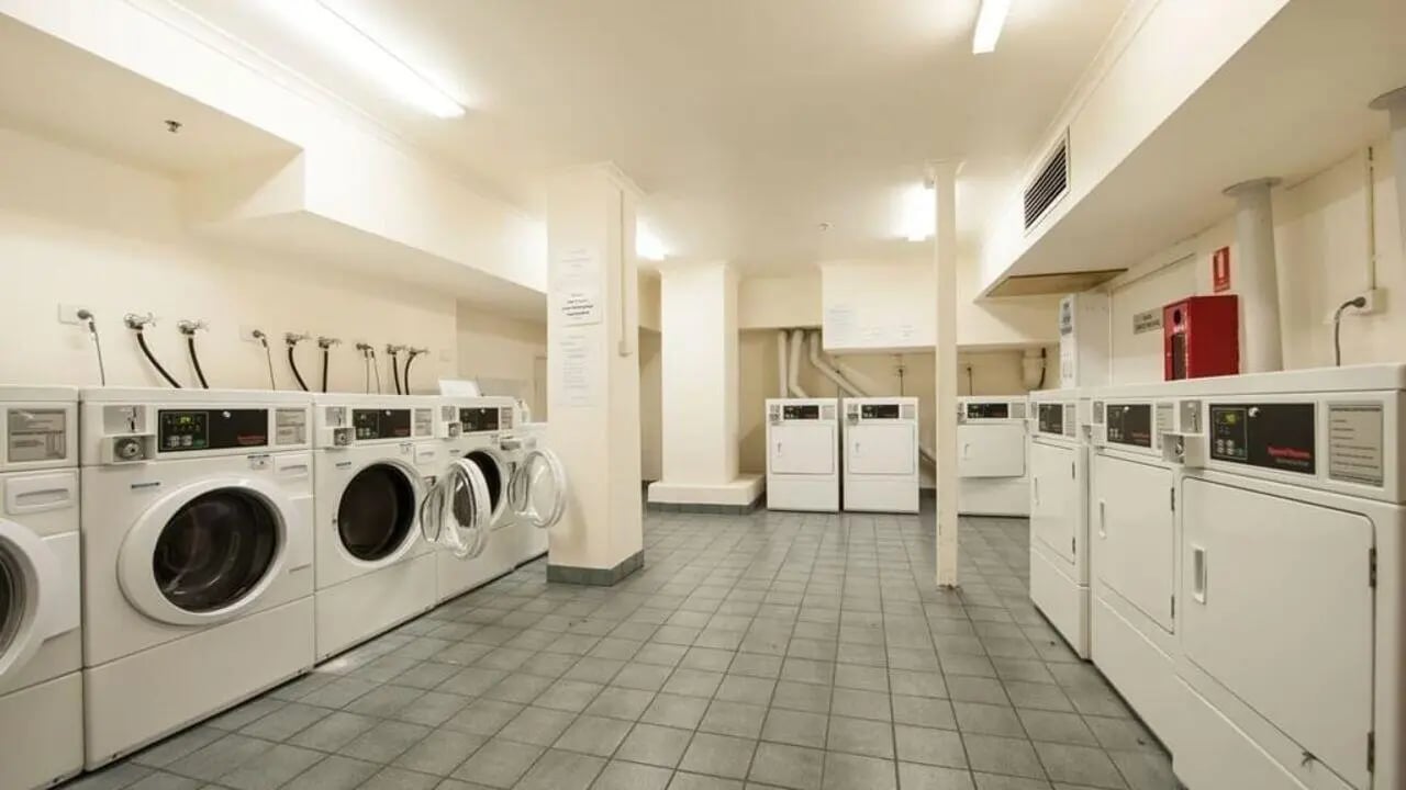 Washing machines and dryers on tiled floor laundry room at Student Living on Flinders in Melbourne Student Accommodation