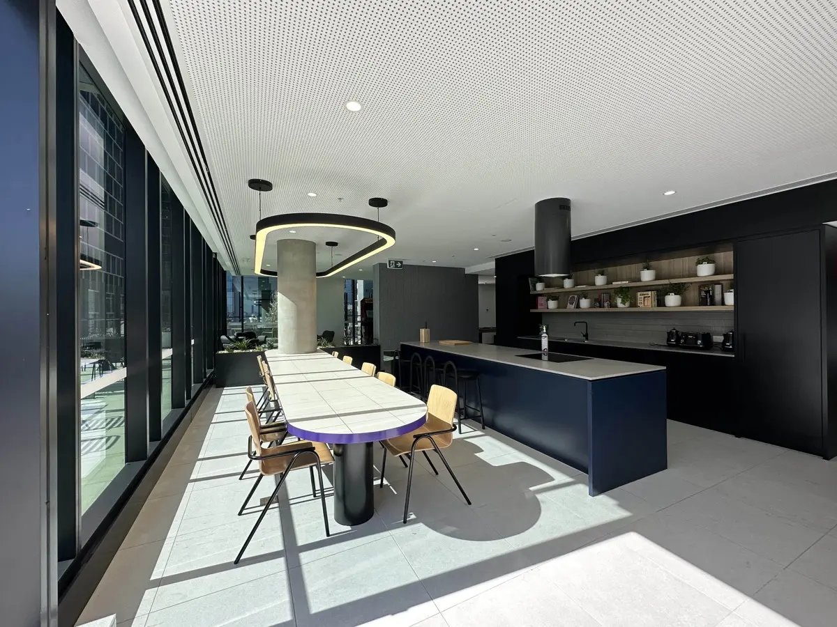 Large dining table with chairs and kitchen island living room at The Switch Melbourne Victoria Market in Melbourne Student Accommodation