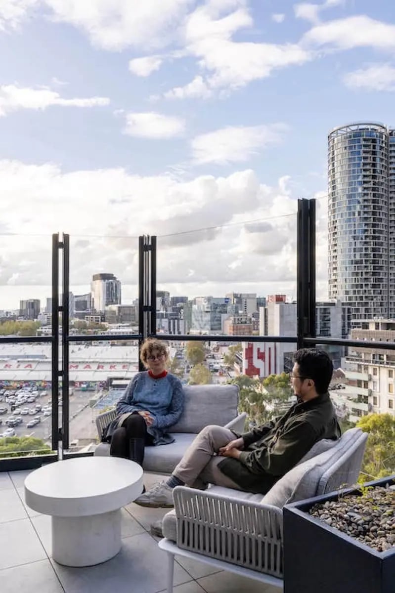 People sitting on balcony furniture city view exterior at The Switch Melbourne Victoria Market in Melbourne Student Accommodation