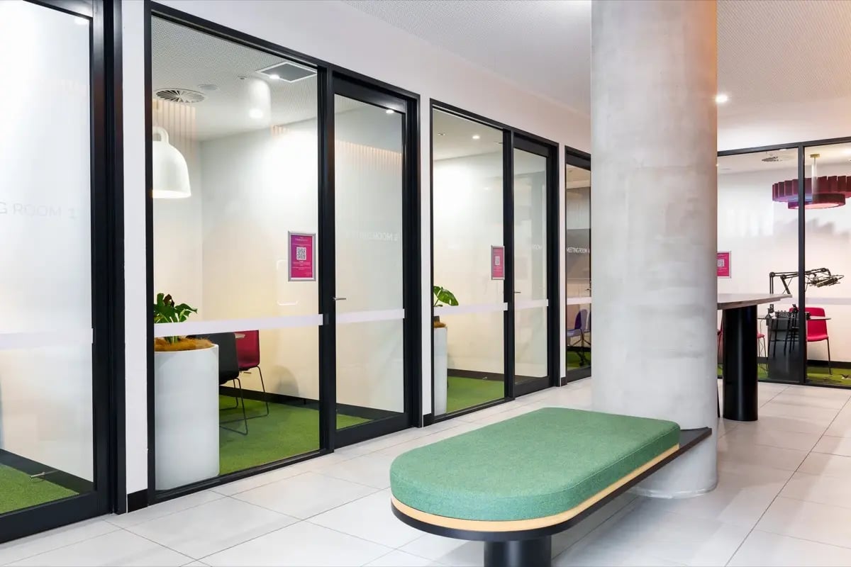 Glass meeting rooms with green carpet and bench common area at The Switch Melbourne Victoria Market in Melbourne Student Accommodation