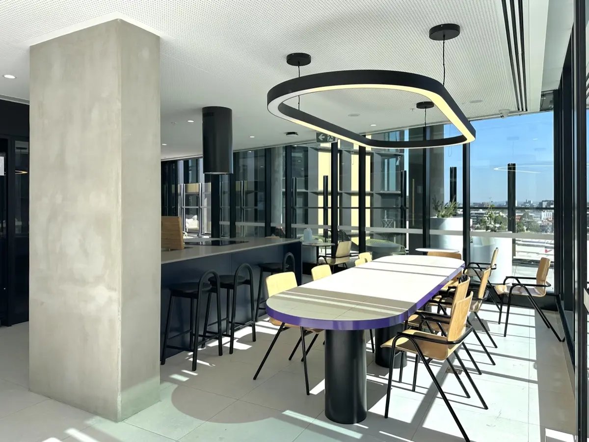 Large dining table with chairs and kitchen communal area at The Switch Melbourne Victoria Market in Melbourne Student Accommodation