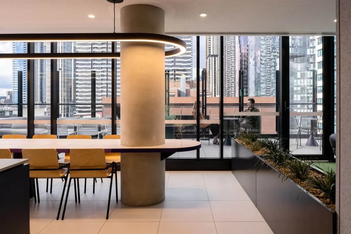 Large dining table with chairs and city view living area at The Switch Melbourne Victoria Market in Melbourne Student Accommodation