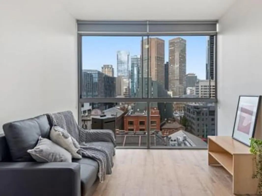 Dark sofa with throw blanket cityscape view living room at Student Living on Lonsdale in Melbourne Student Accommodation