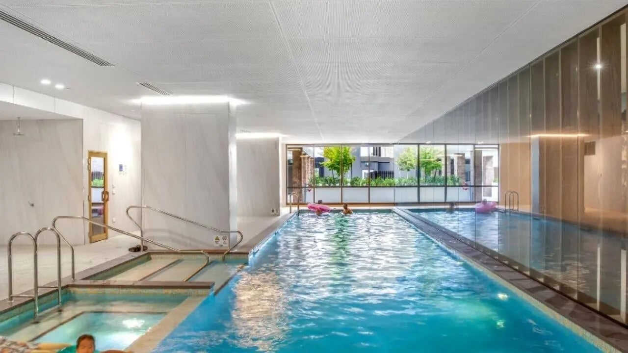 Indoor pool with jacuzzi and people swimming swimming pool at Realm Caulfield in Melbourne Student Accommodation