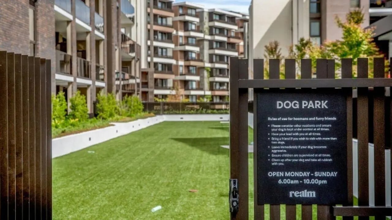 Dog park sign green lawn and apartment buildings exterior at Realm Caulfield in Melbourne Student Accommodation