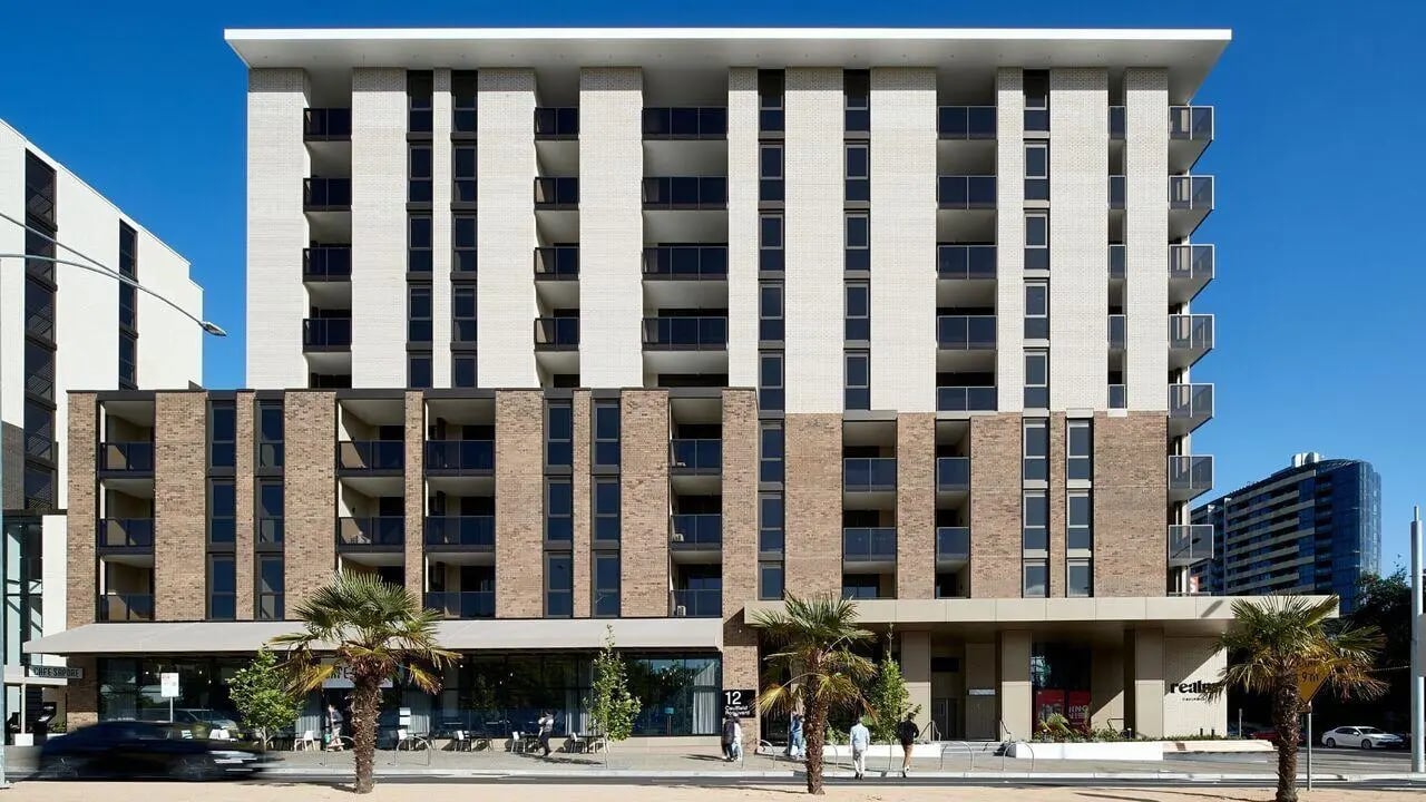 Modern apartment building with balconies and palm trees exterior at Realm Caulfield in Melbourne Student Accommodation