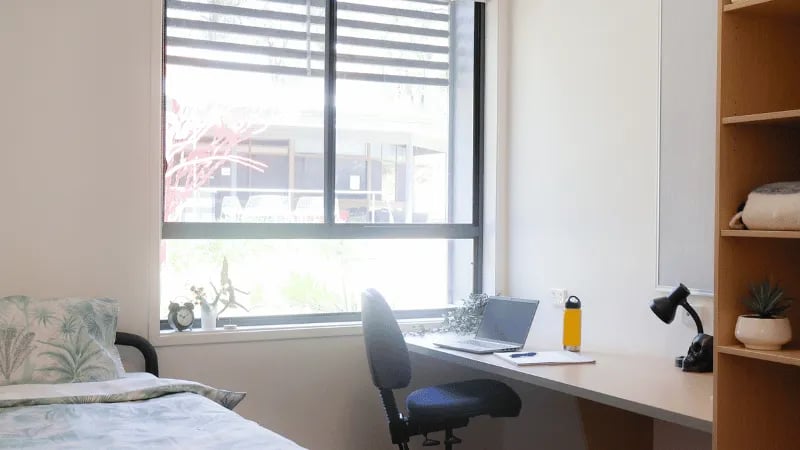 Bed desk with laptop and chair bedroom at La Trobe University - Hillside Apartments in Melbourne Student Accommodation
