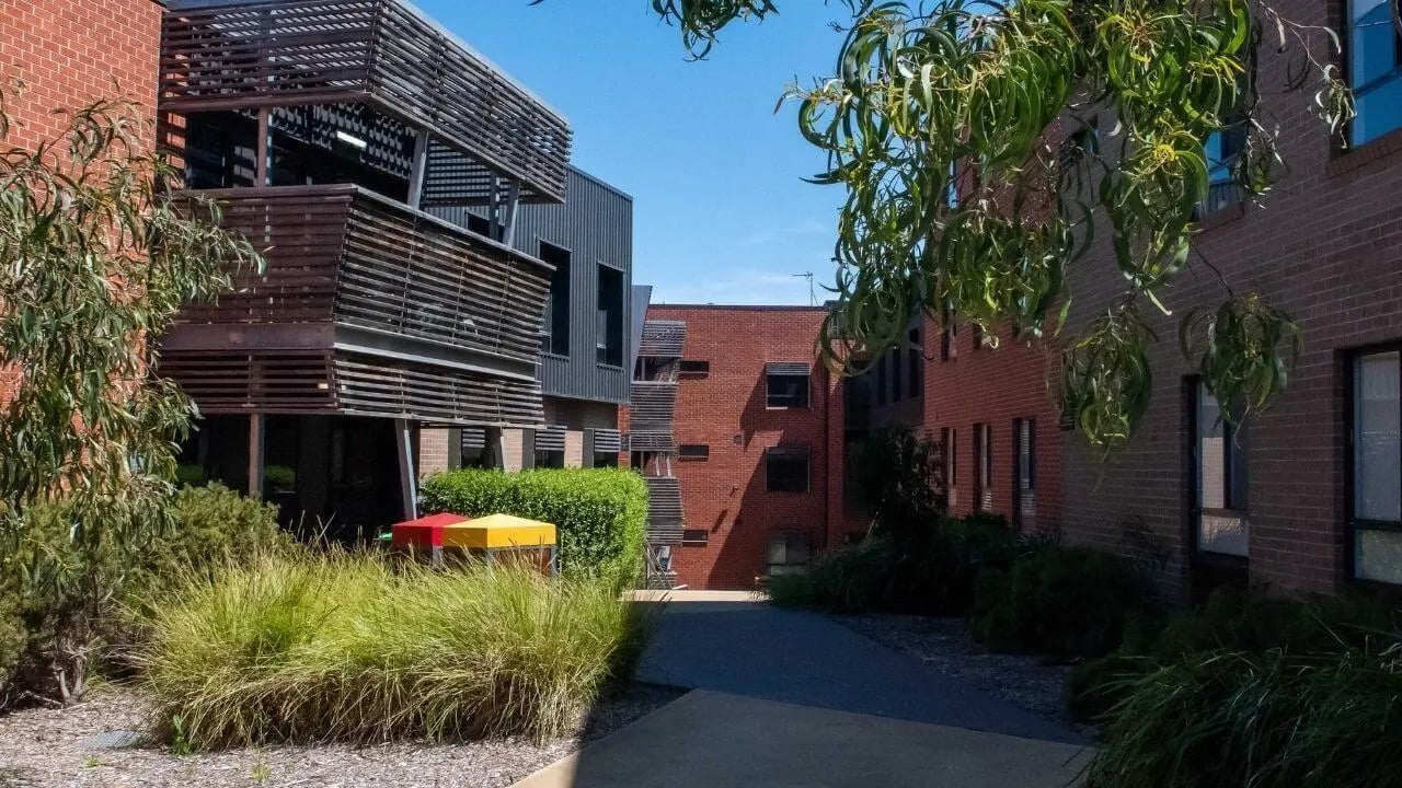 Red brick buildings with outdoor seating exterior at La Trobe University - Hillside Apartments in Melbourne Student Accommodation